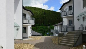 Ein modernes Gebäude mit einem zentralen Innenhof, gepflasterten Wegen und einer Treppe, die in ein Obergeschoss führt.