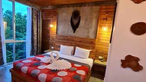 Une chambre spacieuse avec un grand lit, un plafond en bois et une vue sur la verdure environnante.