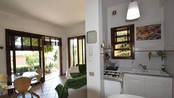 Ein Zimmer mit Essbereich, einem Bett, einer Küche mit Herd und einem Fenster mit Jalousien.