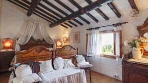 Ein Schlafzimmer mit einem hölzernen Bett, zwei Nachttischen mit Lampen, einem Fenster mit Vorhängen und einem Holzboden.