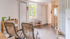 A modern room with a wooden desk, a chair, a small table, and a window with a view of greenery.