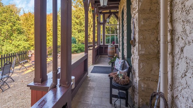 A covered outdoor area with wooden beams, a bench, and a table with a basket.