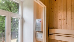 A sauna room with wooden walls, a bench, and a control panel with buttons and a digital display. - Helle Wohnung mit Terrasse und Sauna (Bad Harzburg)