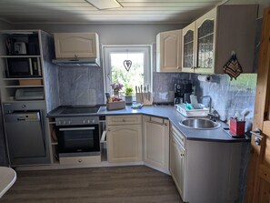 A compact kitchen with a dishwasher, oven, and a coffee machine. - Ferienwohnung in den Hüttenroder Bergen (Hüttenrode)
