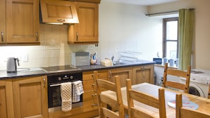 A kitchen with wooden cabinets, a built-in oven, a sink, and a dining table with chairs.