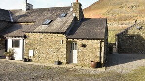 A stone building with a sloped roof, a door, and a small window.