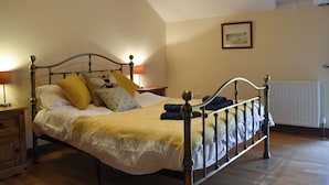 A bedroom with a bed, bedside tables, a lamp, a picture on the wall, and a window.