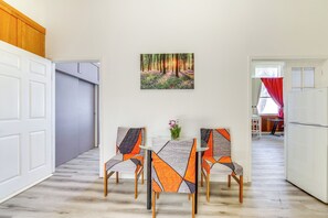 Un área de comedor con una mesa y sillas, un cuadro en la pared y vista a otra habitación.