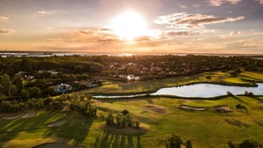 An aerial view of a golf course with a lake, surrounded by residential areas and trees. - Apartment in Albarella near Beach & Activities (Albarella)