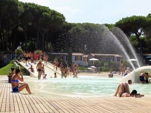 Une zone de baignade publique dotée de plusieurs éléments aquatiques, notamment un toboggan et une fontaine.