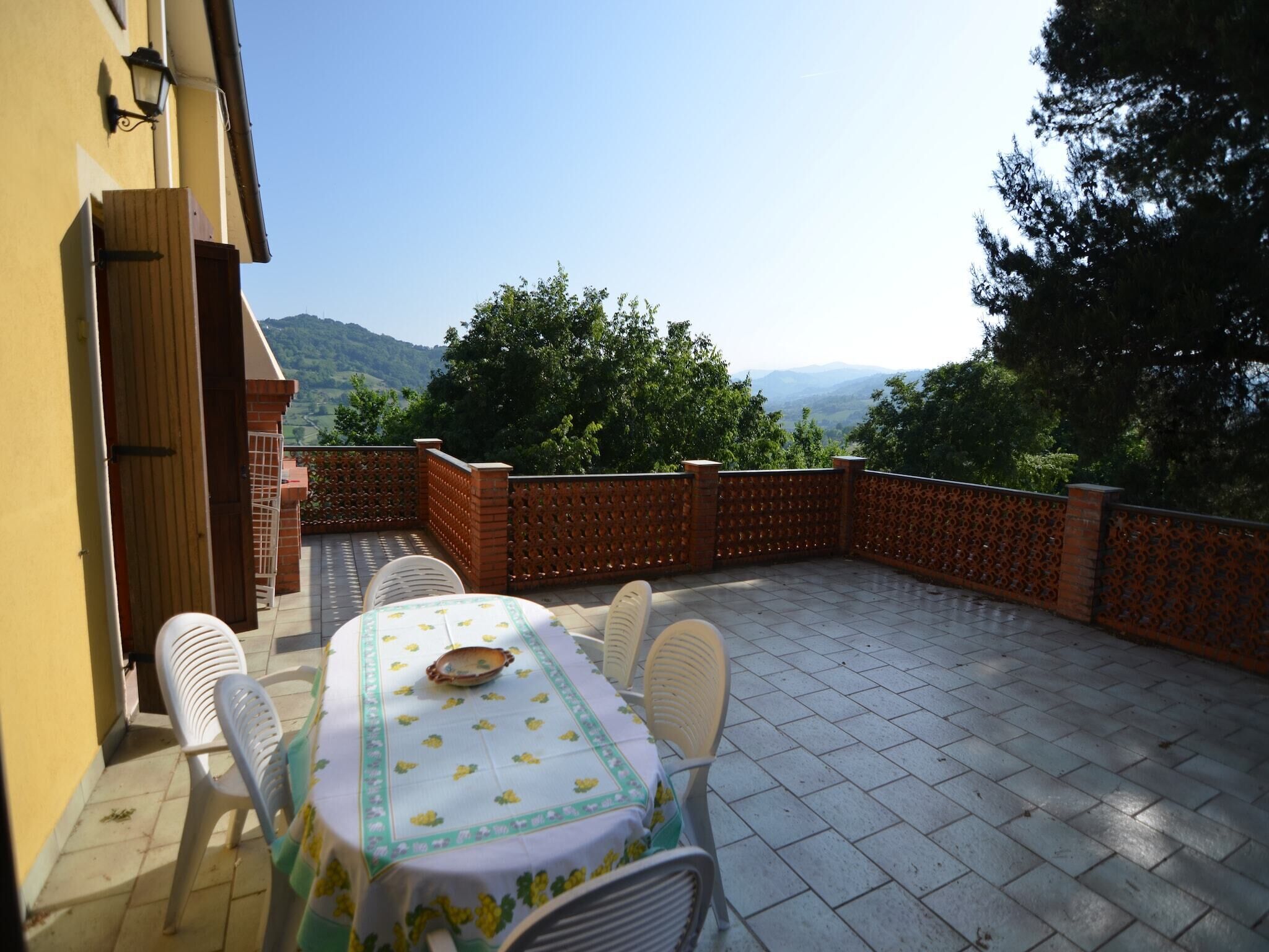 A patio with a table and chairs, a wooden door, and a view of mountains.