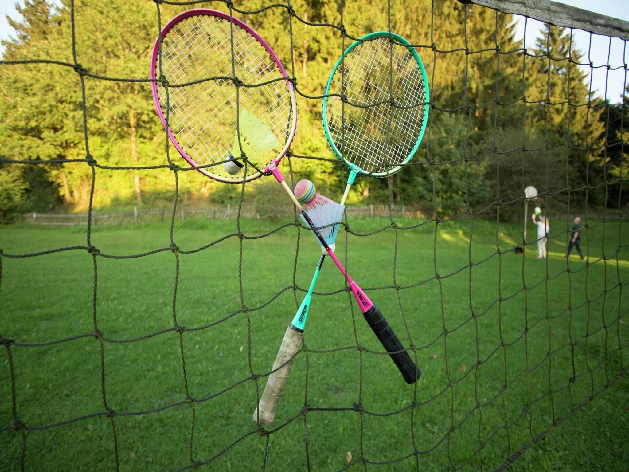A badminton net with two rackets hanging on it.