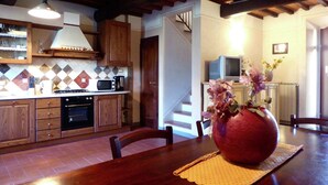 A kitchen with wooden cabinets, a microwave, and a stove. There is a dining table with a vase of flowers.