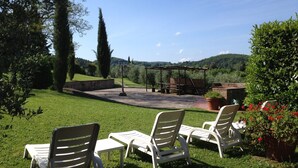 An outdoor seating area with white plastic chairs and tables, a pergola, and a brick structure in the background. - Montaione Oasis: Shared Villa (Montaione)