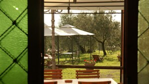 An outdoor dining area with tables and chairs, umbrellas, and potted plants. - Belvilla by OYO Istrice (Capraia E Limite (fi))