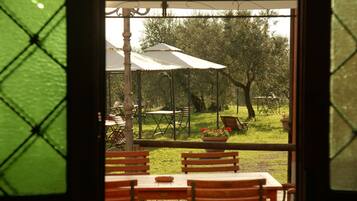 Un'area pranzo all'aperto con tavoli, sedie, ombrelloni e piante in vaso.