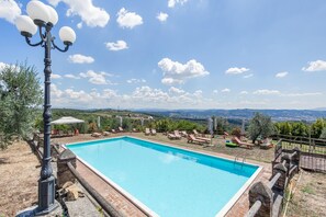 A rectangular swimming pool with a clear blue water surface, surrounded by a stone wall and a wooden deck.