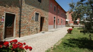 A stone building with a red facade, a gravel pathway, and potted plants. - Belvilla by OYO Istrice (Capraia E Limite (fi))