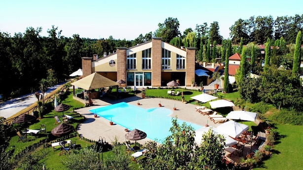 Een modern hotel met een zwembad, terras en een verzorgde tuin.