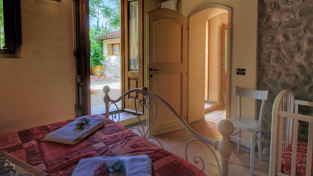 Ein Schlafzimmer mit Bett, Nachttisch, Sessel und Blick ins Freie.