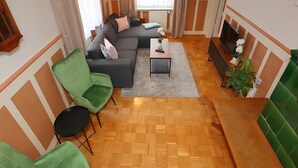 A modern living room with a sofa, green armchairs, a coffee table, and a TV.