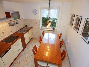 Une cuisine moderne avec une table et des chaises en bois, un four encastré et une fenêtre donnant sur un paysage verdoyant.