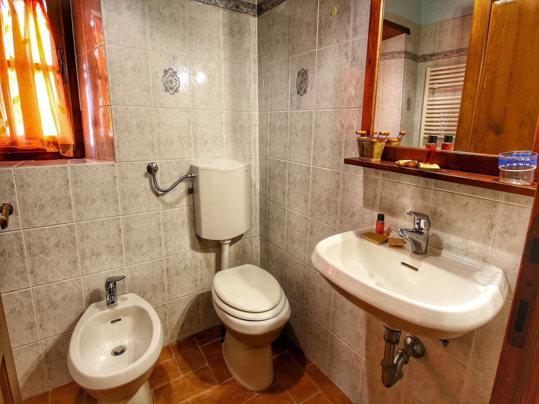A bathroom with a toilet, bidet, sink, and a mirror above the sink.