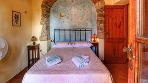 A bedroom with a bed, a nightstand, a lamp, and a wooden door. - Chianti Hillside Farmhouse (Radda in Chianti)
