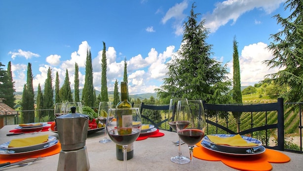 An outdoor dining area with a scenic view, featuring a table set with plates, glasses, and a bottle of wine. - Chianti Hillside Farmhouse (Radda in Chianti)