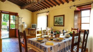 A dining area with a table set for four, a chandelier, a painting on the wall, and a television in the corner. - Chianti Hillside Farmhouse (Radda in Chianti)
