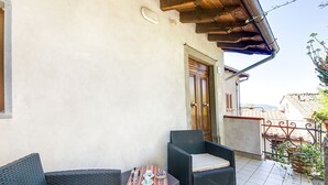 Ein Balkon mit Korbmöbeln, Fliesenboden und Holztür.