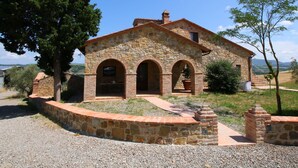Un edificio de piedra con una entrada central arqueada, una pequeña torre y un camino de grava.