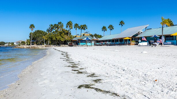 Ein Strandhotel mit überdachtem Essbereich, Sitzgelegenheiten im Freien und Blick auf den Ozean.