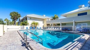 Ein Schwimmbecken mit Liegestühlen und einer überdachten Terrasse.