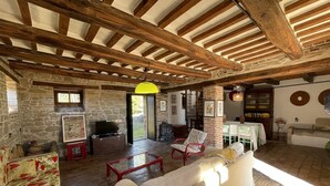 A rustic interior with exposed wooden beams, stone walls, a fireplace, and a sofa.