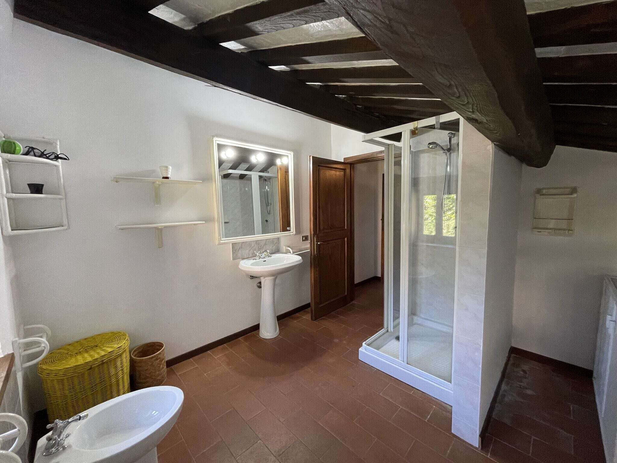 Une salle de bain avec un lavabo blanc, un miroir et une cabine de douche.