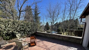 Une terrasse avec une chaise en métal, une table en bois et un mur en pierre.
