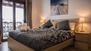 A bedroom with a large bed, two bedside lamps, a headboard, and a painting of a beach scene. - Terrace Stay Close to Beaches (Playa Blanca)