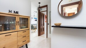 Un pasillo con un armario de madera identificado con la etiqueta 'HOME', un espejo y una cesta sobre un estante negro.