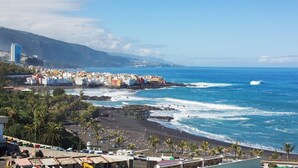 Un pueblo costero con edificios a lo largo de la playa, una vista despejada del océano y un litoral rocoso.