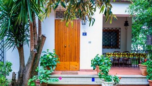 A wooden door, potted plants, and outdoor seating.