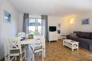 A living room with a dining area, a television, and a sofa.