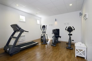 Ein Fitnessraum mit Laufband, Crosstrainer und Ergometer.