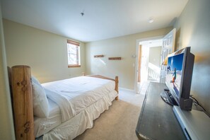 Een slaapkamer met een bed, een televisie en een deur naar een andere kamer.