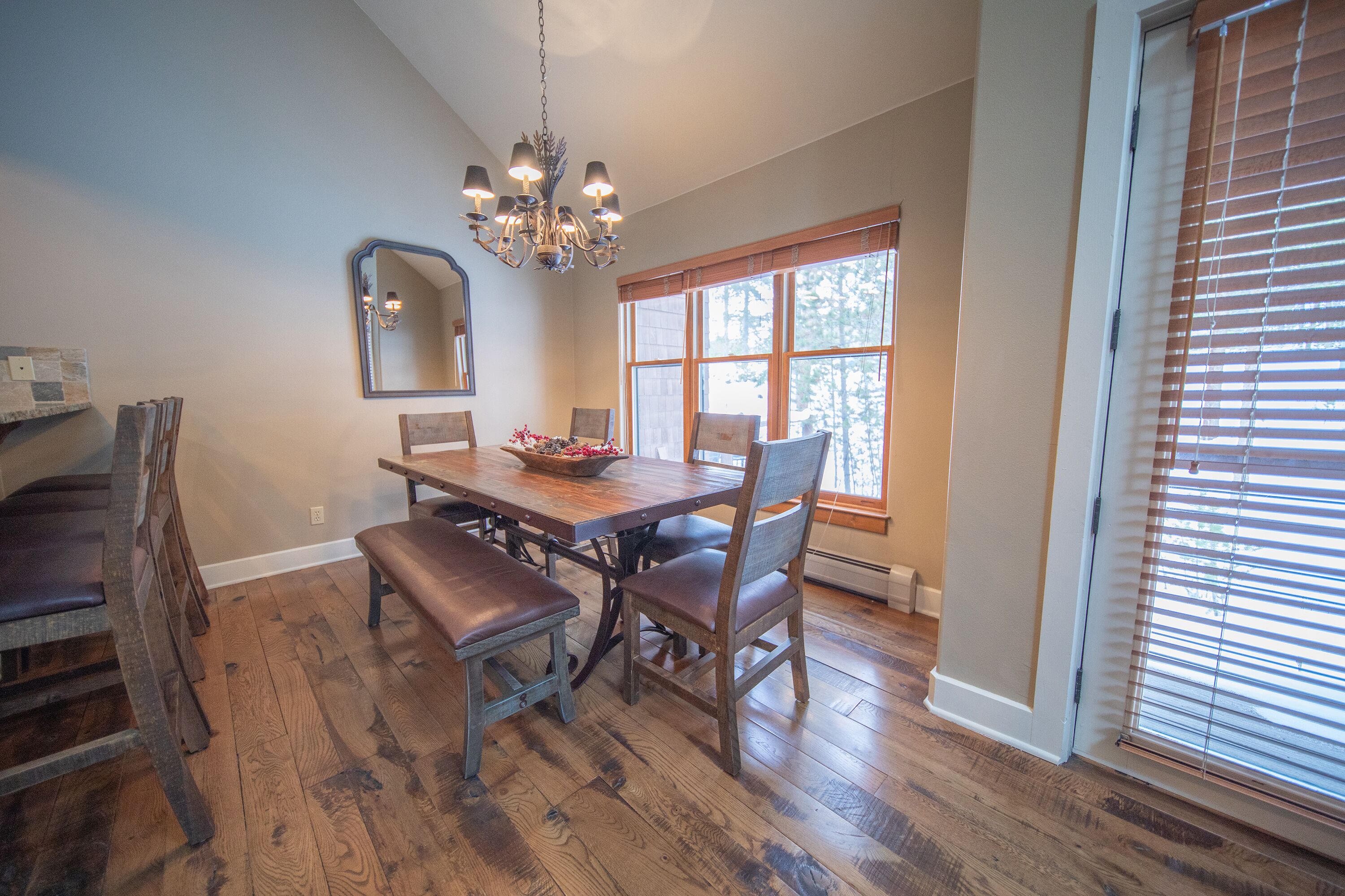 A dining area with a wooden table, benches, and a chandelier.