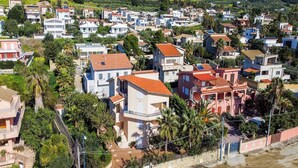 A residential area with houses, some with red roofs, and a white car parked on the street.
