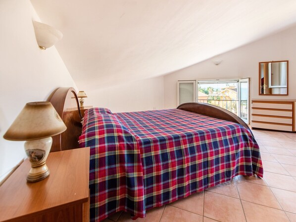 Un dormitorio con cama, mesita de noche, lámpara, cómoda y ventana con vistas.