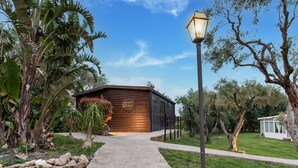 Een houten gebouw met een pad van stenen er naartoe, omringd door weelderige begroeiing en een heldere lucht.