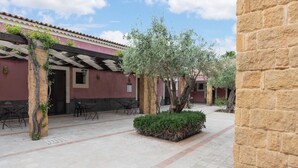 A courtyard with stone pillars, outdoor seating, and a tree. - Holiday Home near Mount Etna Views (Carlentini)