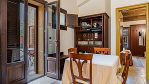 A dining area with a table set for two, wooden chairs, a wooden cabinet with dishes, and a glass door leading outside. - Holiday Home near Mount Etna Views (Carlentini)